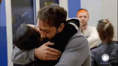 A Man Is Hugging A Woman In Front Of A Recordtv Logo GIF