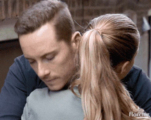 A Man Is Hugging A Woman With The Word Florchz On The Bottom Right GIF