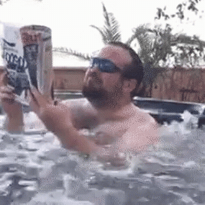 A Man Is In A Hot Tub Reading A Magazine GIF
