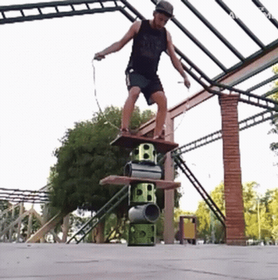 A Man Is Jumping A Rope While Standing On A Stack Of Barrels With The Letter B On Them GIF