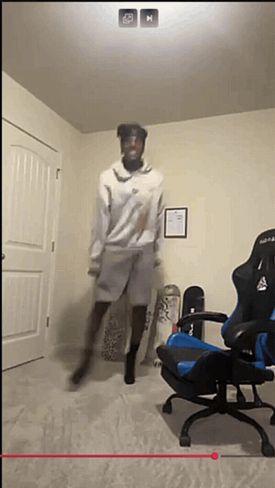 A Man Is Jumping In The Air In A Room With A Chair And Skateboards GIF