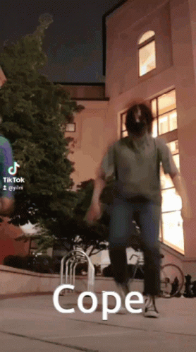A Man Is Jumping In The Air In Front Of A Building With The Words Cope Written On The Ground . GIF