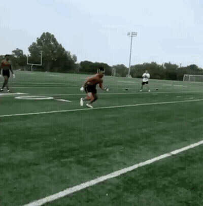 A Man Is Jumping In The Air On A Football Field GIF