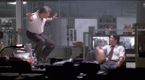 A Man Is Jumping In The Air While Another Man Sits In A Chair GIF