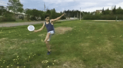 A Man Is Jumping In The Air While Holding A Frisbee In A Field GIF