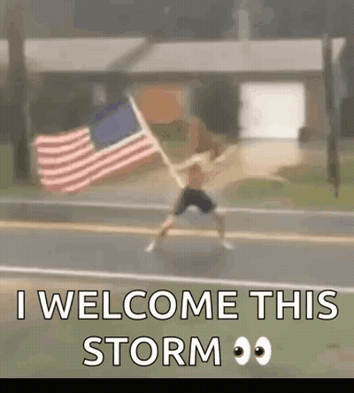 A Man Is Jumping In The Air While Holding An American Flag In Front Of A House . GIF