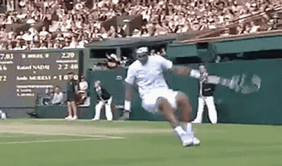 A Man Is Jumping In The Air While Playing Tennis On A Court . GIF