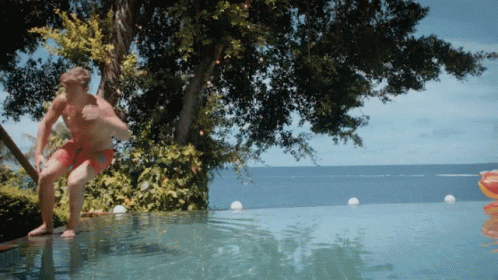 A Man Is Jumping Into An Infinity Pool GIF