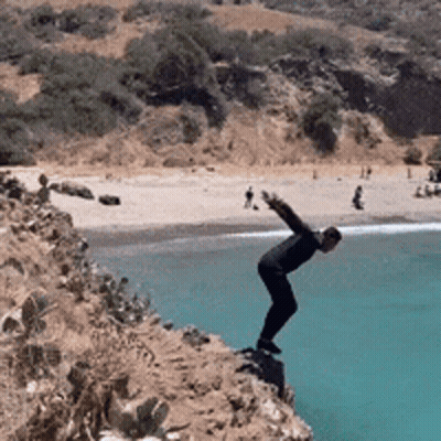 A Man Is Jumping Into The Ocean From A Cliff GIF