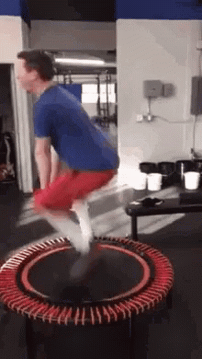 A Man Is Jumping On A Mini Trampoline In A Gym . GIF