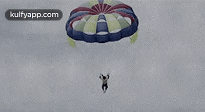 A Man Is Jumping Out Of A Parachute Into The Air . GIF