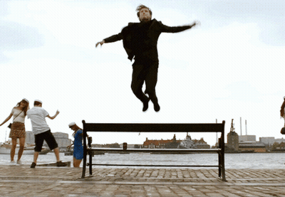 A Man Is Jumping Over A Bench In The Air GIF