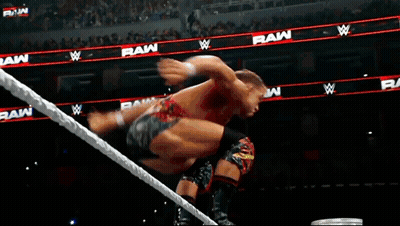 A Man Is Jumping Over A Rope In A Wrestling Ring With The Word Raw In The Background GIF