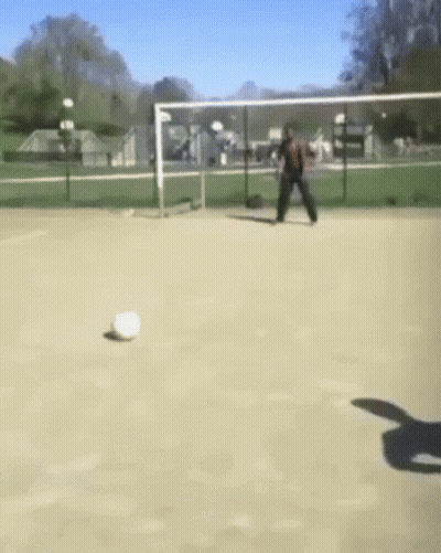 A Man Is Kicking A Soccer Ball In A Field GIF