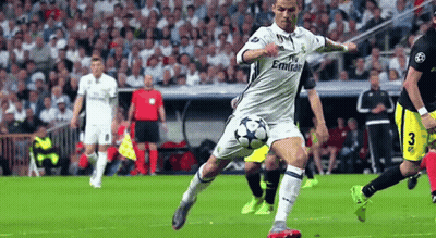 A Man Is Kicking A Soccer Ball On A Field . GIF