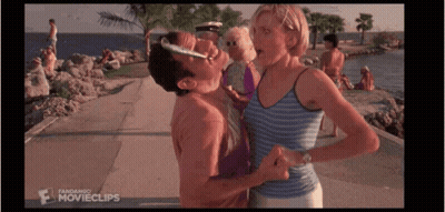 A Man Is Kissing A Woman On The Cheek While Standing On A Beach . GIF