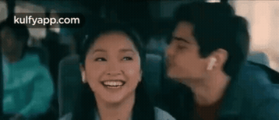 A Man Is Kissing A Woman On The Cheek While They Are Sitting In A Car . GIF
