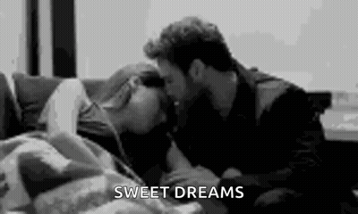 A Man Is Kissing A Woman On The Forehead On A Couch . GIF
