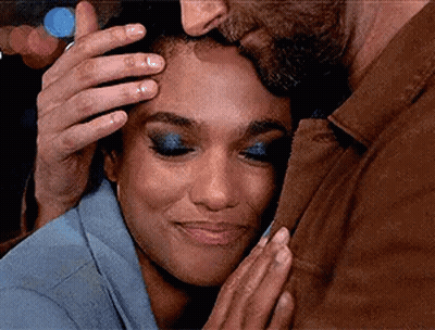 A Man Is Kissing A Woman On The Forehead While The Woman Is Smiling . GIF
