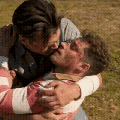 A Man Is Kissing Another Man On The Forehead While They Are Hugging Each Other . GIF