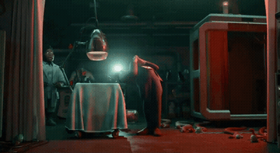 A Man Is Kneeling Down In A Dark Room With A Light Shining On His Head GIF