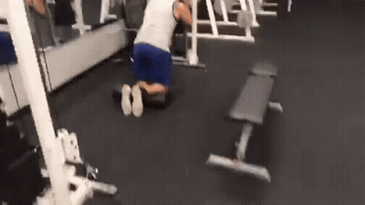 A Man Is Kneeling Down In A Gym With A Bench In The Background . GIF