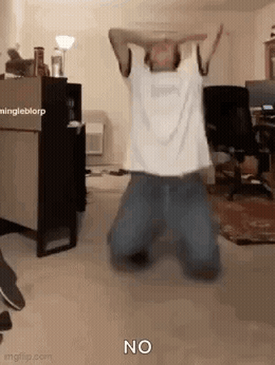 A Man Is Kneeling Down In A Room With His Arms In The Air And The Word No On The Floor . GIF