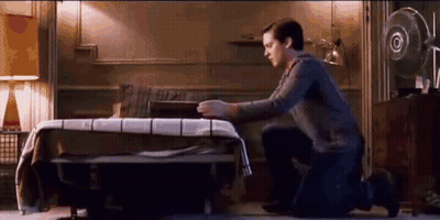 A Man Is Kneeling Down In Front Of A Bed In A Bedroom . GIF
