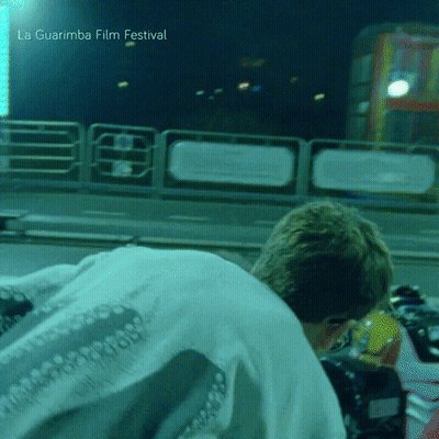 A Man Is Kneeling Down In Front Of A La Guarimba Film Festival Sign GIF