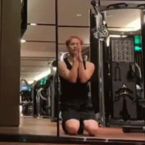 A Man Is Kneeling Down In Front Of A Mirror In A Gym And Praying . GIF