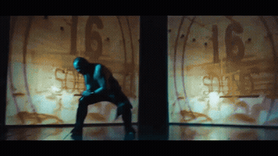 A Man Is Kneeling Down In Front Of A Wall With The Number 16 Written On It GIF