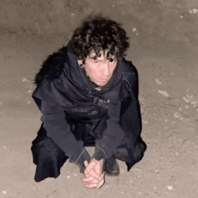 A Man Is Kneeling Down On The Ground With His Hands Folded . GIF