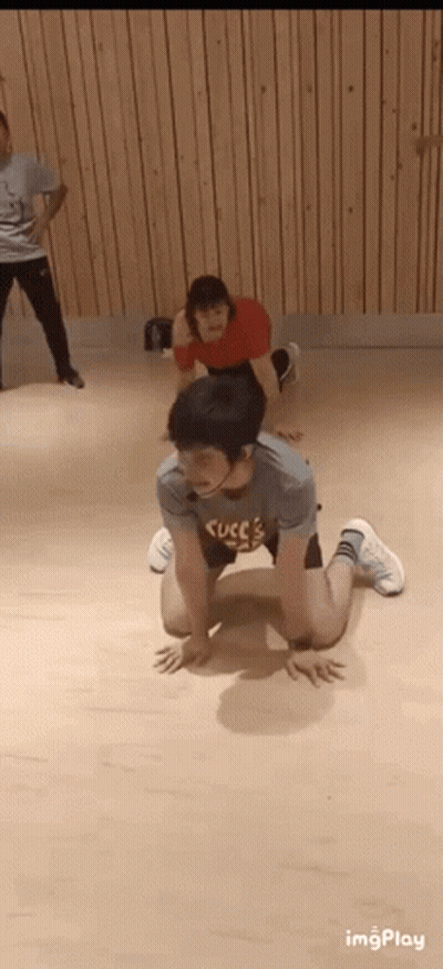 A Man Is Kneeling On The Floor In A Dance Studio While A Woman Stands Behind Him . GIF