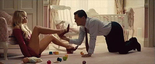 A Man Is Kneeling On The Floor While A Woman Sits In A Chair . GIF