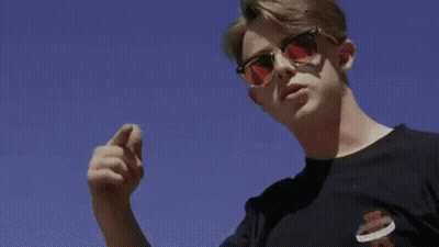 A Man Is Kneeling On The Ground In Front Of A Large Building . GIF