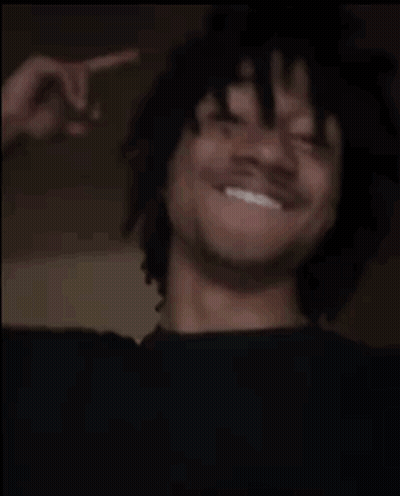 A Man Is Laughing And Giving The Middle Finger While Wearing A Black Shirt . GIF