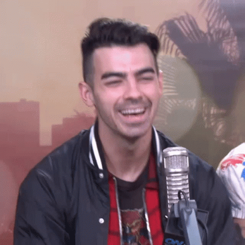A Man Is Laughing In Front Of A Microphone . GIF