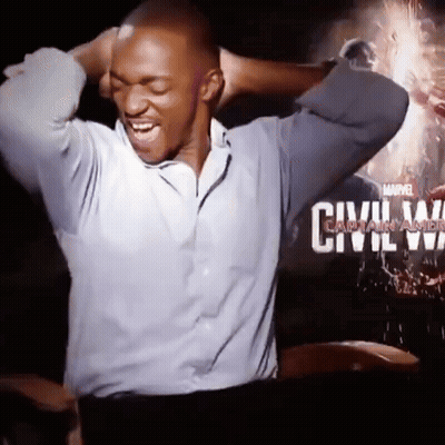 A Man Is Laughing In Front Of A Movie Poster For Civil War GIF