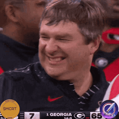 A Man Is Laughing In Front Of A Scoreboard That Says Georgia GIF