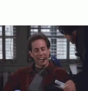 A Man Is Laughing While Another Man Is Holding A Piece Of Paper In His Hand . GIF