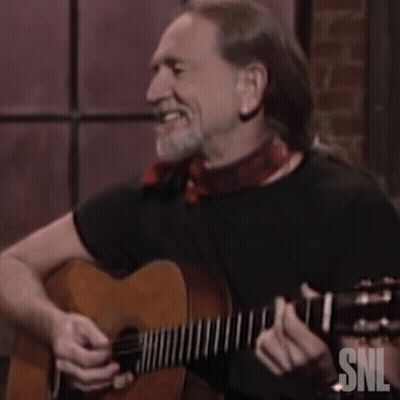 A Man Is Laughing While Playing A Guitar With Snl Written On It GIF
