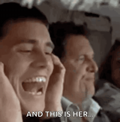 A Man Is Laughing While Sitting Next To Another Man On A Plane While Holding His Hands To His Ears . GIF