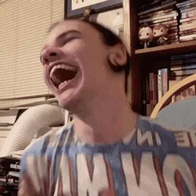 A Man Is Laughing With His Mouth Open And Wearing A T-Shirt That Says Nirvana . GIF