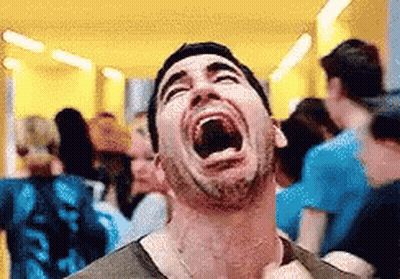 A Man Is Laughing With His Mouth Wide Open In A Crowd Of People . GIF