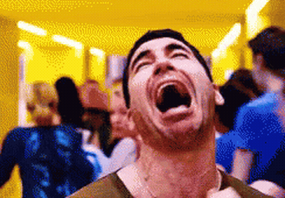 A Man Is Laughing With His Mouth Wide Open In A Crowded Room . GIF