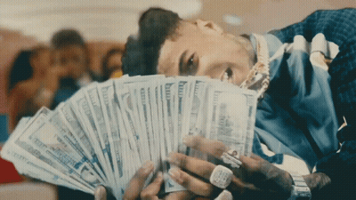 A Man Is Laying Down Holding A Fan Of Money In His Hands GIF