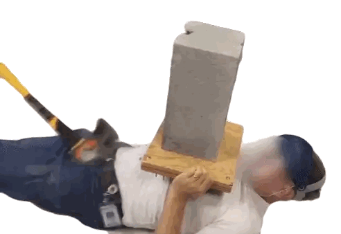A Man Is Laying Down With A Hammer And A Brick On His Back GIF