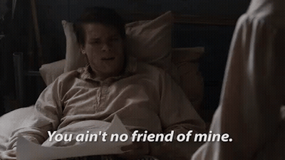 A Man Is Laying In A Bed With A Piece Of Paper And A Woman Is Standing Next To Him . GIF