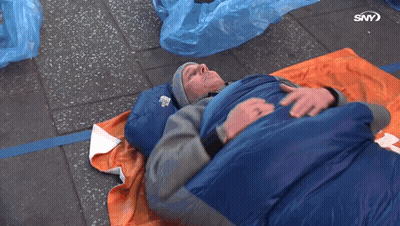 A Man Is Laying In A Blue Sleeping Bag With The Letters Sny On The Bottom Of The Image GIF
