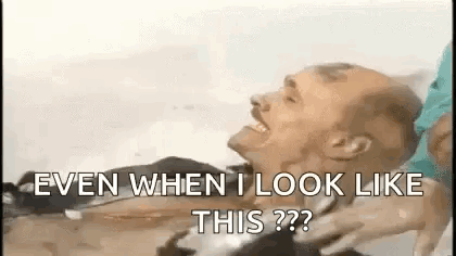 A Man Is Laying In A Hospital Bed And Laughing While A Woman Holds His Neck . GIF